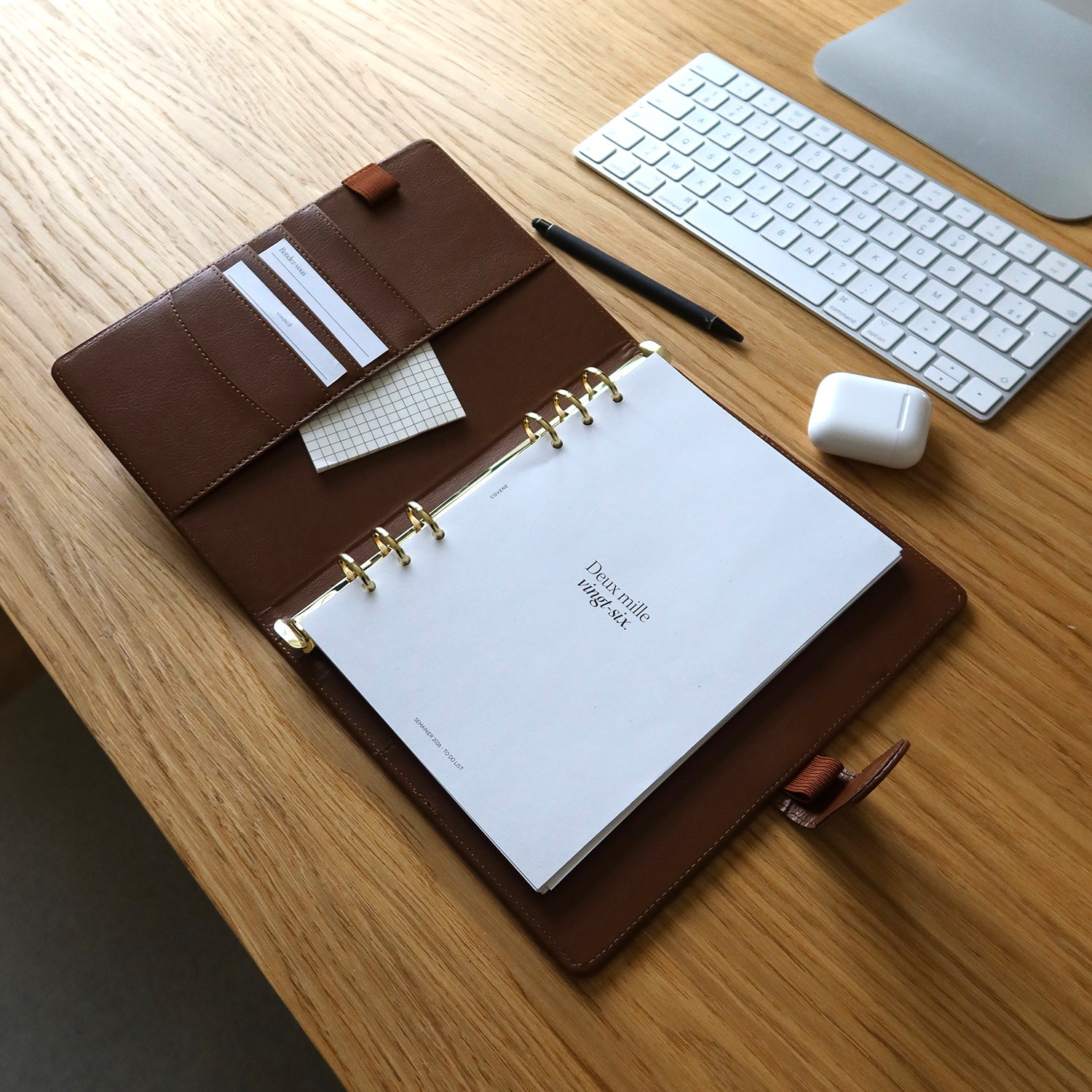 agenda couverture à 6 anneaux, posé sur un bureau avec un crayon et des écouteurs sans fils. Couverture anneaux pour composer soi même son agenda selon ses besoins