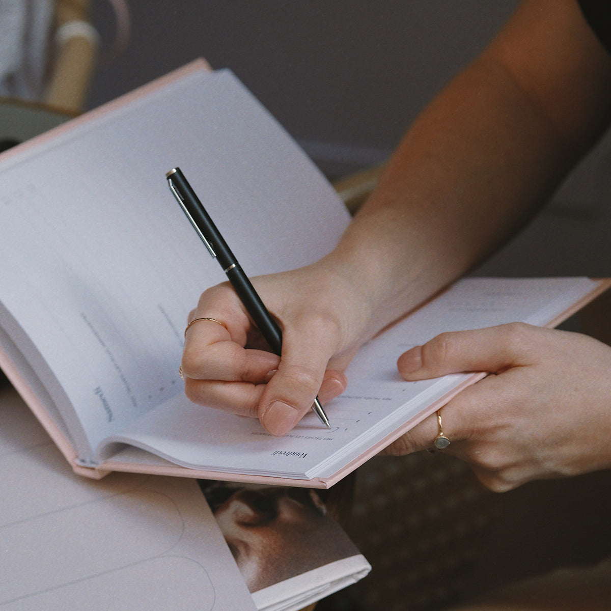 une femme qui écrit dans un carnet de productivité rose