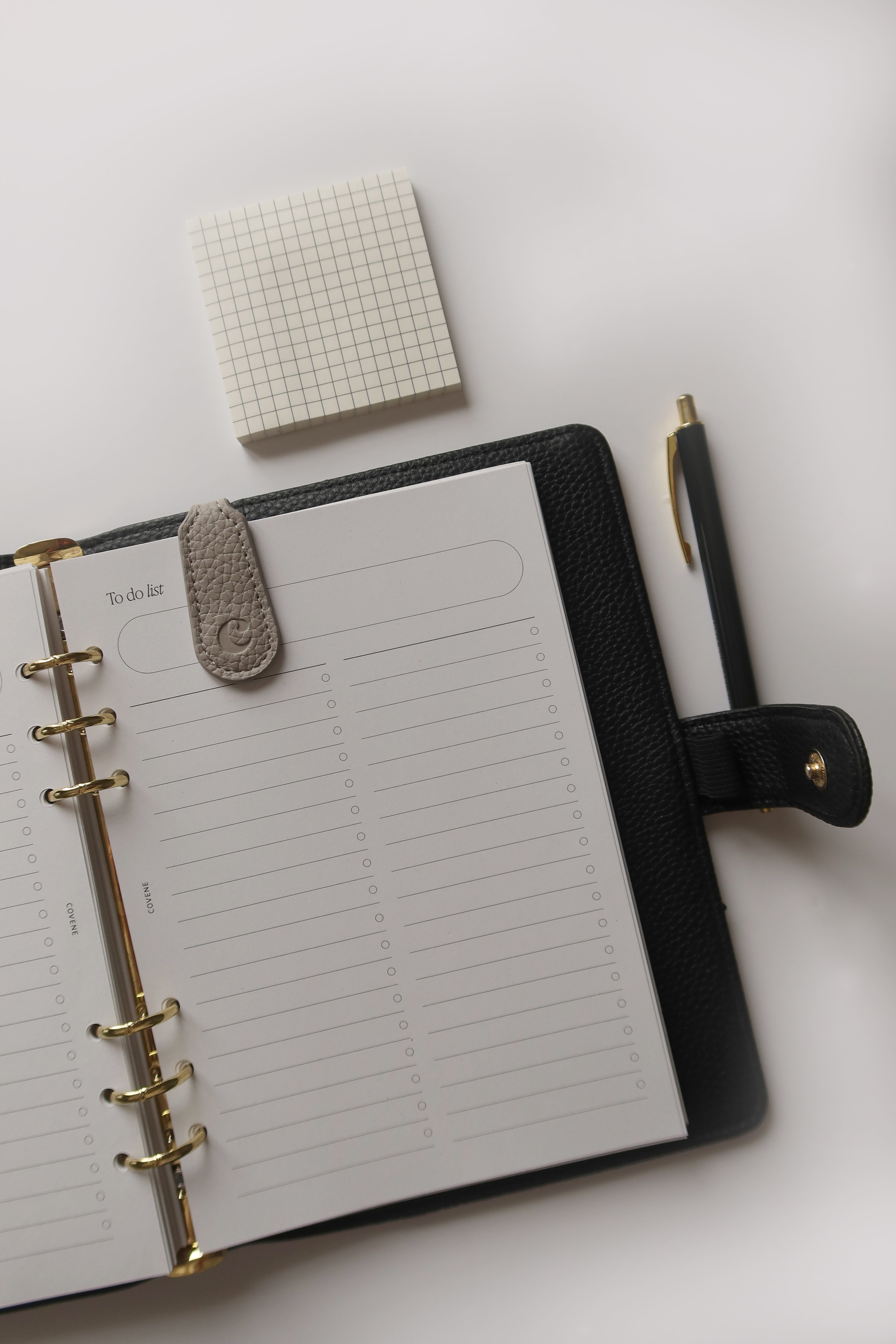 visuel d'un agenda posé sur une table blanche, un bloc post-it a carreaux et un stylo sont posés à coté, un marque page magnétique aimanté est fixé sur l'agenda à la page d'une to do list Image