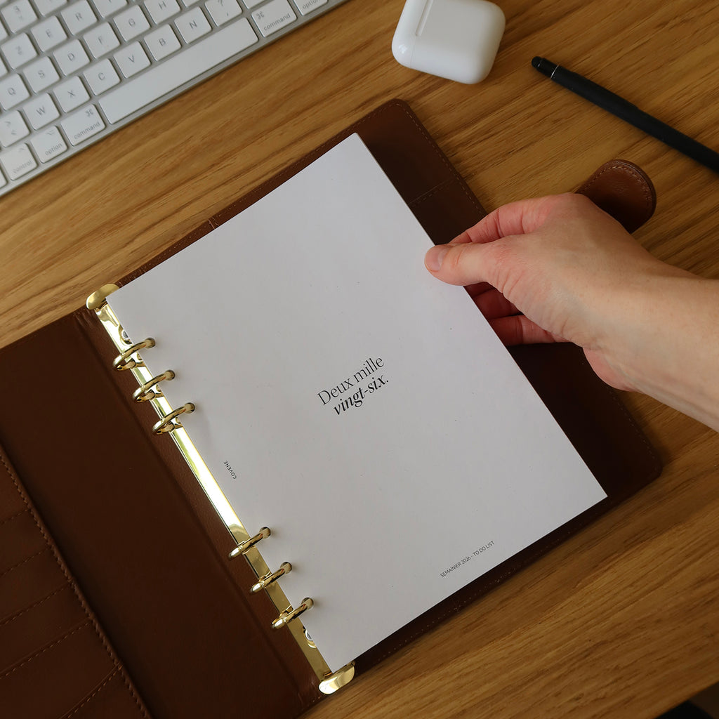agenda couverture à 6 anneaux, posé sur un bureau avec un crayon et des écouteurs sans fils. Couverture anneaux pour composer soi même son agenda selon ses besoins