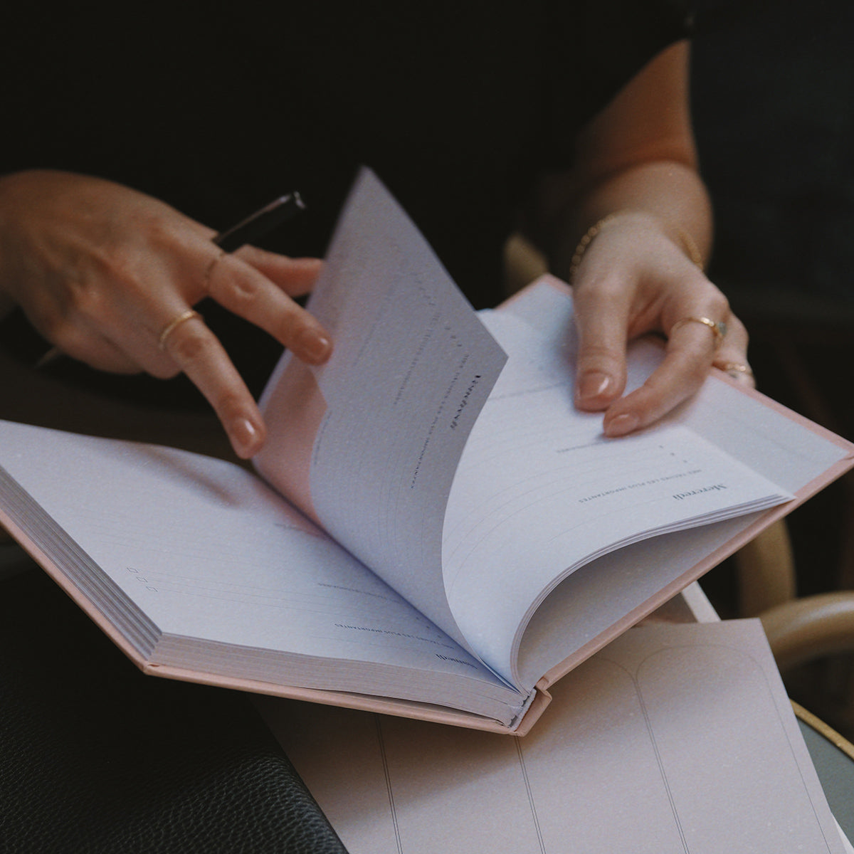 une femme qui écrit dans un carnet de productivité rose, focus du jour, objectifs, entrepreneurs