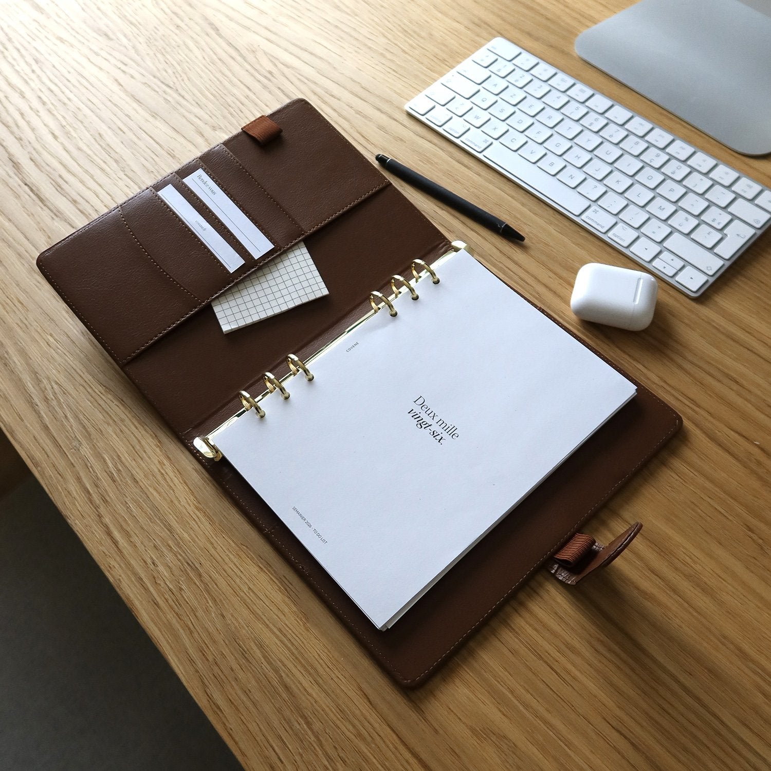 agenda couverture à 6 anneaux, posé sur un bureau avec un crayon et des écouteurs sans fils. Couverture anneaux pour composer soi même son agenda selon ses besoins